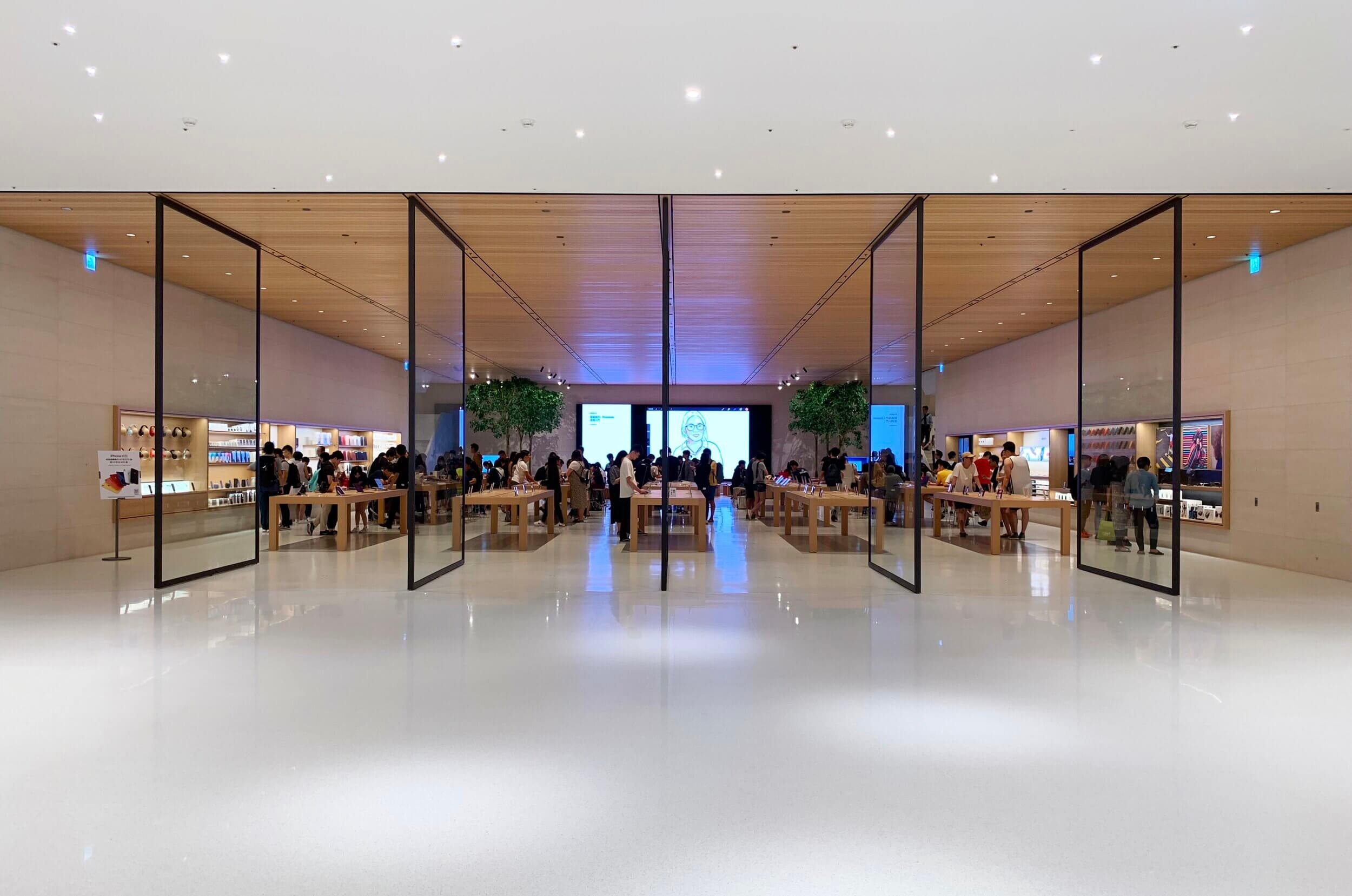 Bright, modern retail store filled with customers and wooden tables displaying products.